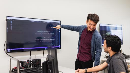 student pointing to code on monitor